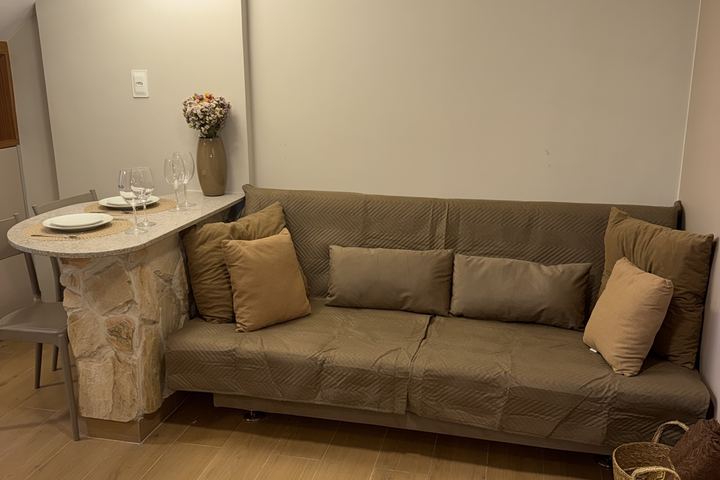 Sala com sofá-cama marrom e bancada de pedra ao fundo