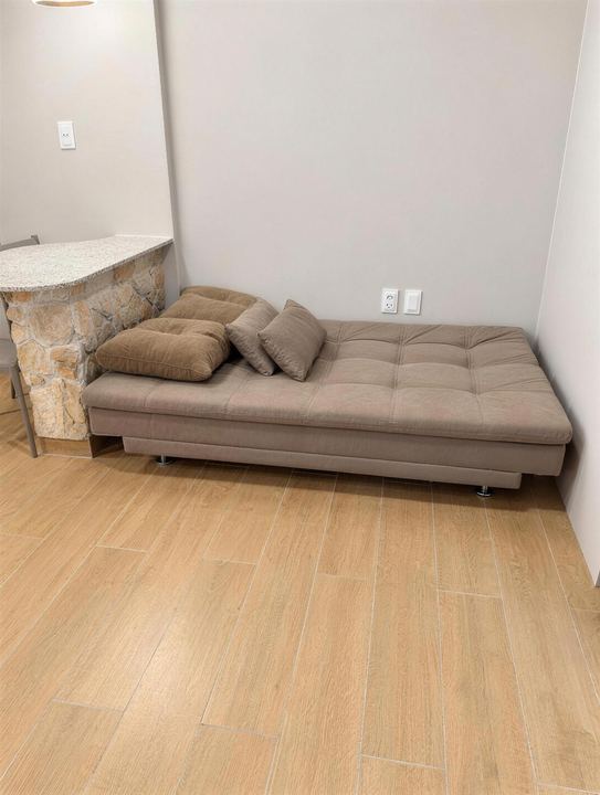 Sofá-cama de tecido bege em frente à bancada de pedra