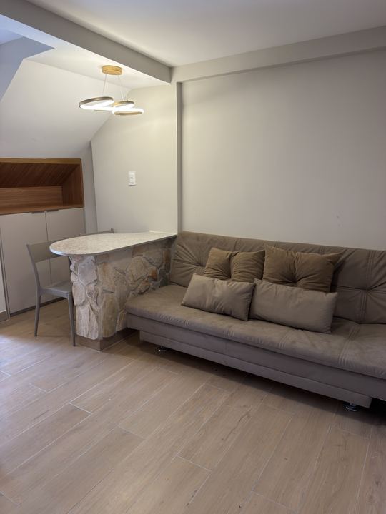 Sala integrada com sofá-cama, mesa de jantar e luminária
