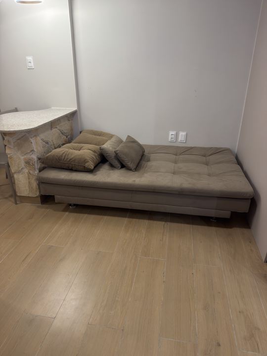 Sofá-cama com almofadas e piso amadeirado