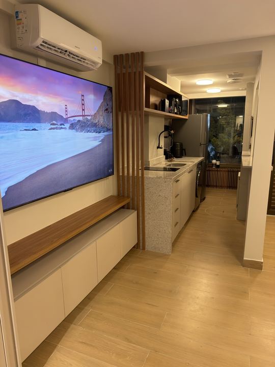 TV na parede com painel ripado e bancada da cozinha