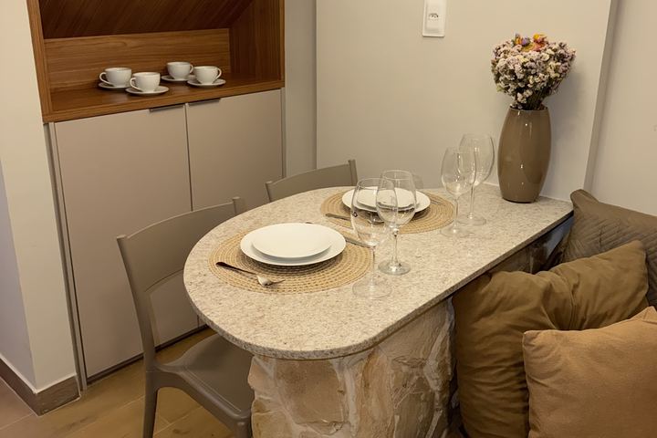Mesa posta com louça e taças junto ao nicho de madeira