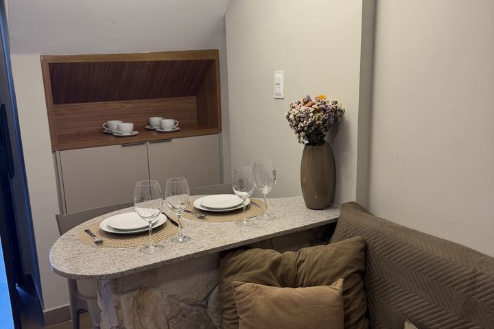 Mesa posta com taças, nicho de madeira e vaso de flores