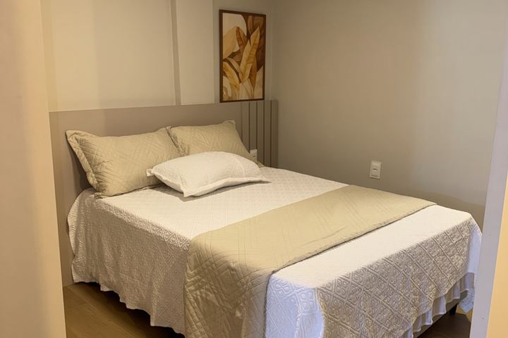 Cama de casal com roupa de cama branca e cabeceira estofada