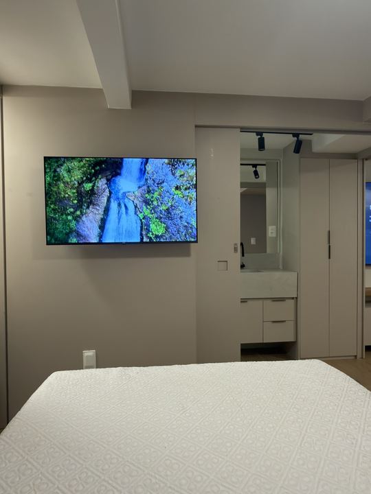 Quarto com TV na parede e mesa de trabalho