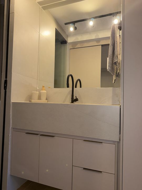 Banheiro com bancada, espelho e iluminação em trilho