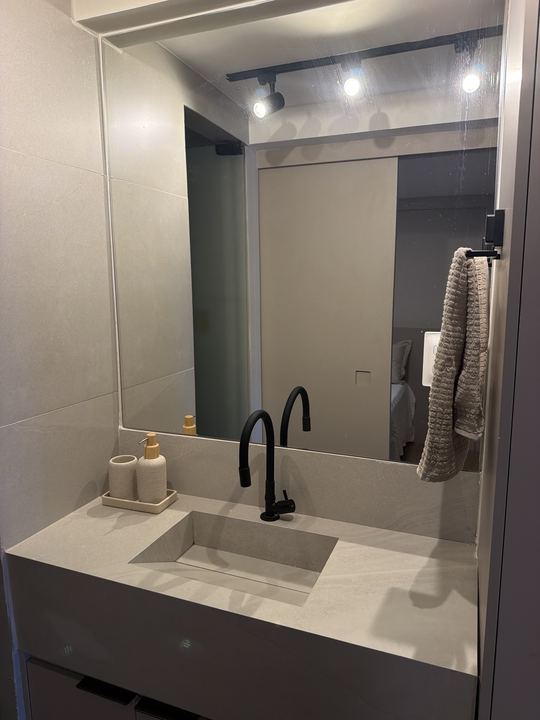 Banheiro com bancada branca e torneira preta