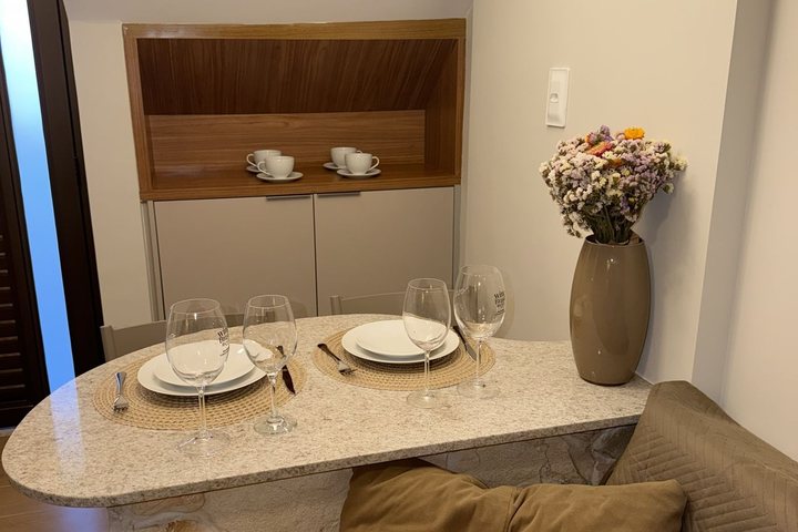 Nicho de madeira com xícaras e mesa posta com vaso de flores