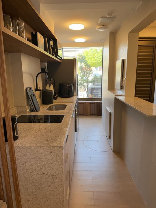 Cozinha em corredor com cooktop, prateleiras de madeira e janela