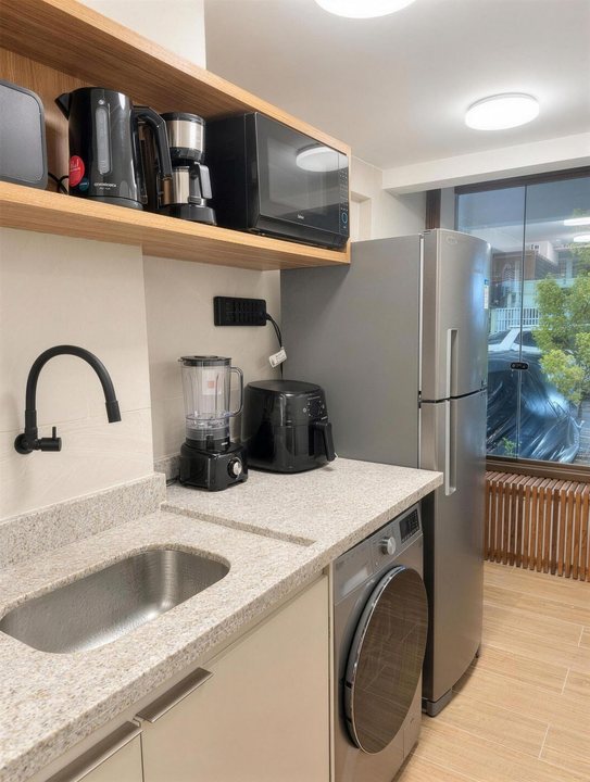 Cozinha com cafeteiras, micro-ondas, liquidificador, lava e seca e geladeira
