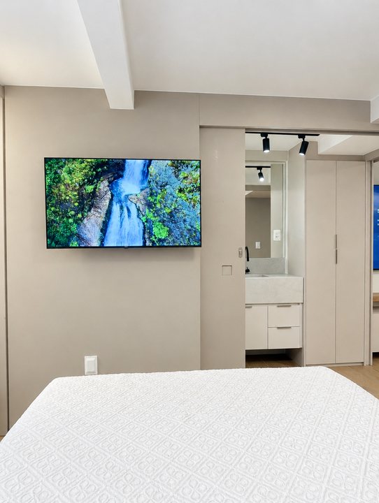 Quarto com TV na parede e cama de casal