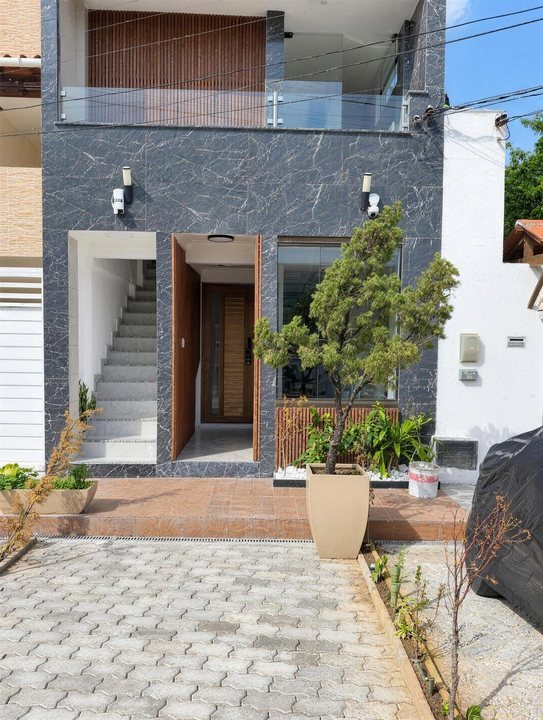 Fachada do prédio com revestimento de pedra, porta de madeira e vaso